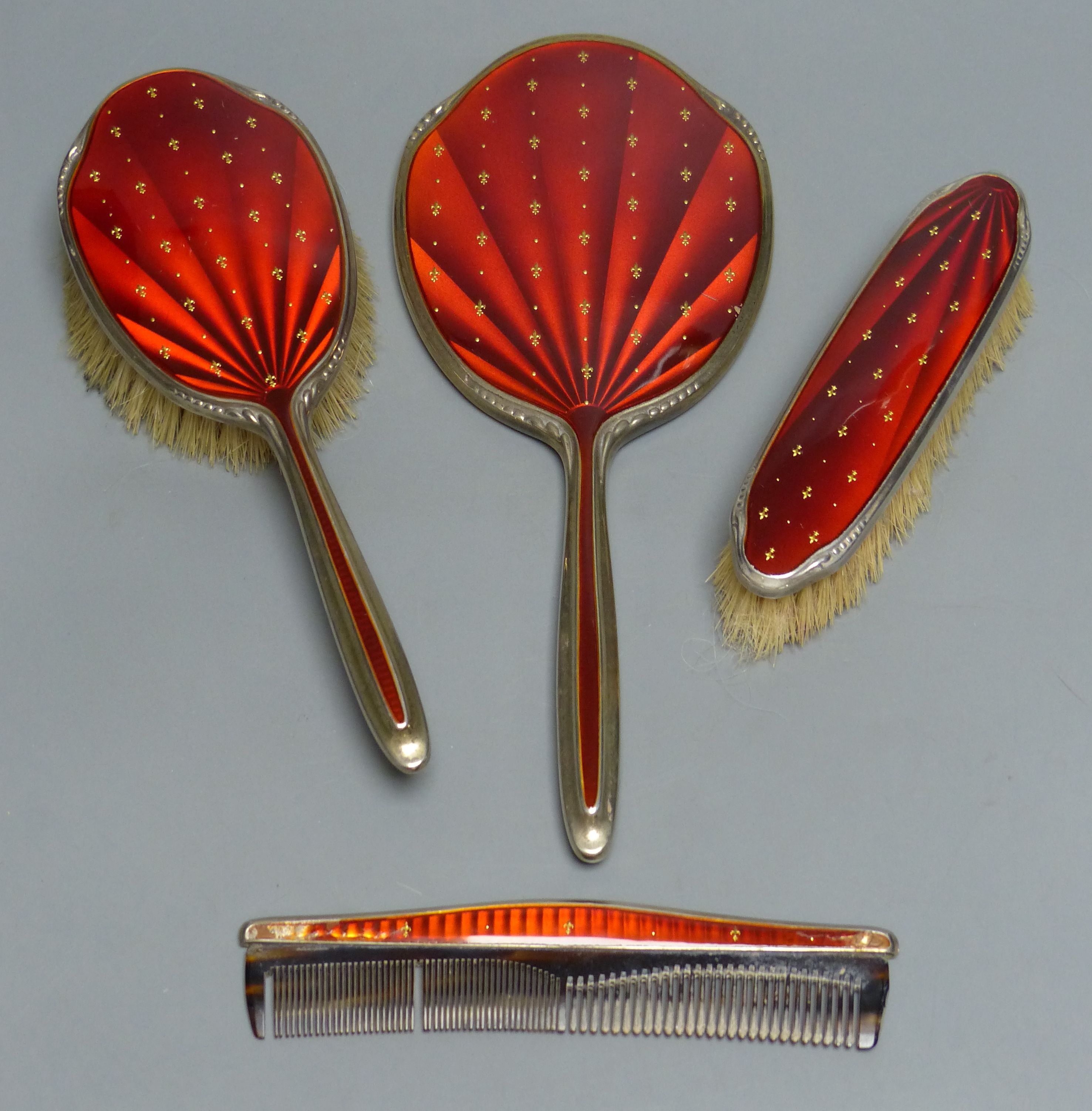 A four-piece silver-gilt and scarlet enamel-mounted dressing table set with fleur de lys decoration, Birmingham 1965